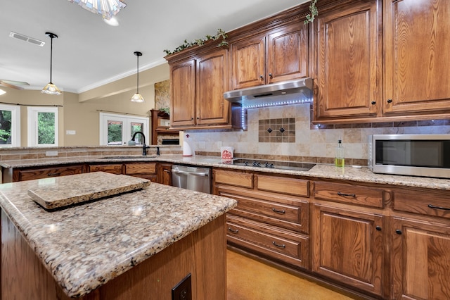 kitchen with hanging light fixtures, sink, tasteful backsplash, appliances with stainless steel finishes, and a center island