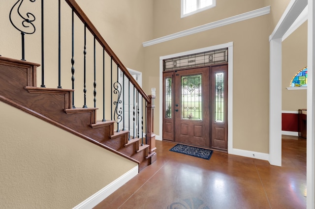 foyer entrance featuring a towering ceiling, concrete floors, and plenty of natural light