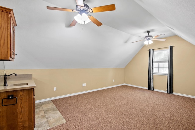 additional living space with vaulted ceiling, sink, ceiling fan, and light colored carpet