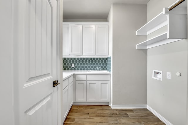 washroom featuring cabinets, sink, hookup for a washing machine, and light wood-type flooring