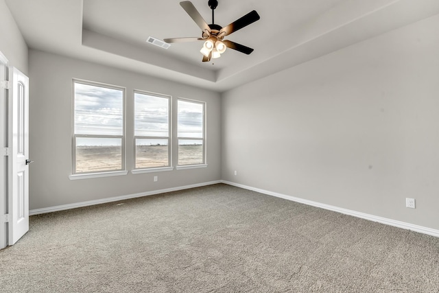 spare room featuring ceiling fan, a tray ceiling, and carpet floors