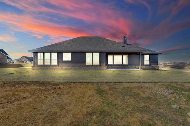 back house at dusk featuring a yard