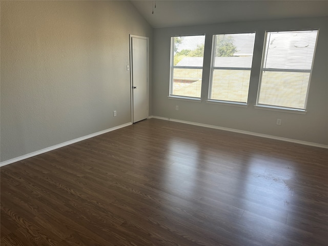 spare room featuring lofted ceiling and dark hardwood / wood-style flooring