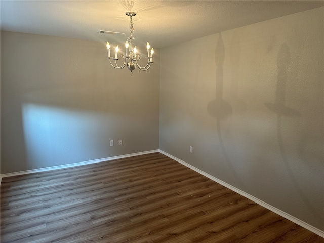 empty room featuring an inviting chandelier and dark wood-type flooring