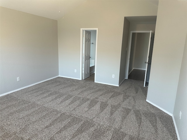 unfurnished bedroom featuring ensuite bath and dark colored carpet