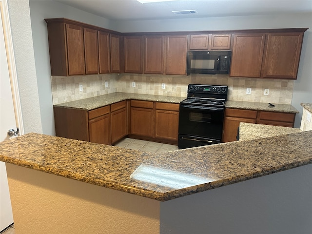 kitchen featuring dark stone counters, light tile patterned floors, decorative backsplash, and black appliances