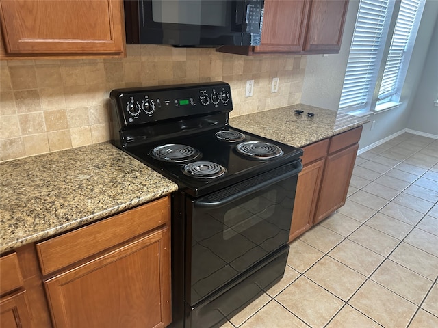 kitchen with light stone countertops, decorative backsplash, black appliances, and light tile patterned floors