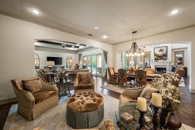 living room featuring ceiling fan with notable chandelier, a tile fireplace, hardwood / wood-style floors, and crown molding