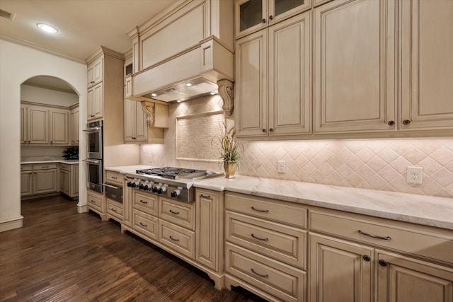 kitchen with light stone countertops, backsplash, appliances with stainless steel finishes, and dark wood-type flooring