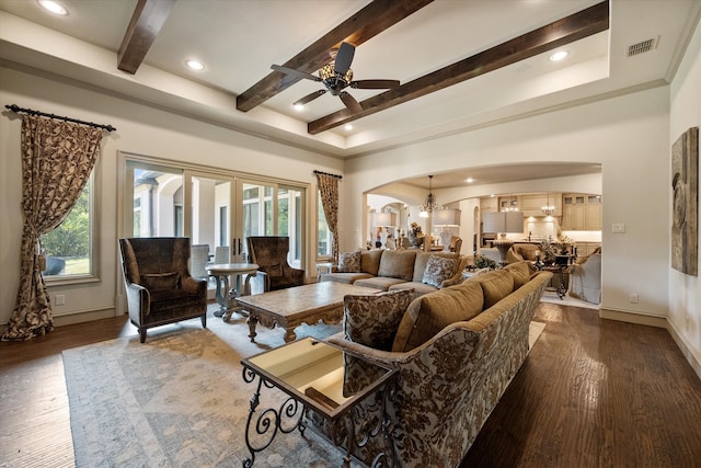 living room featuring beamed ceiling, ceiling fan with notable chandelier, and dark hardwood / wood-style floors