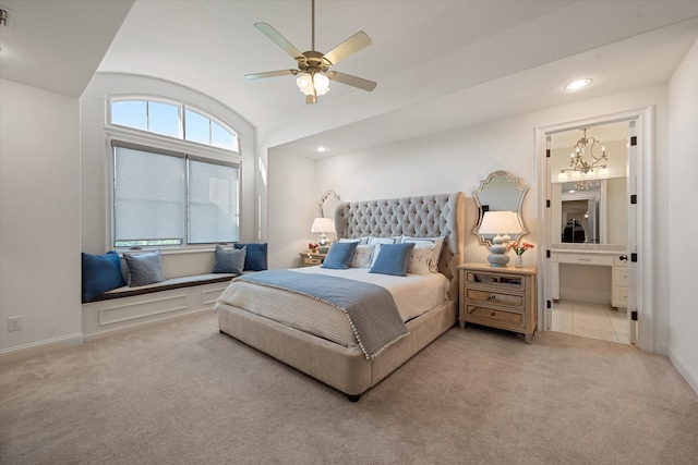 carpeted bedroom featuring ceiling fan with notable chandelier and ensuite bath