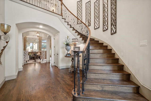 staircase with a towering ceiling and hardwood / wood-style floors