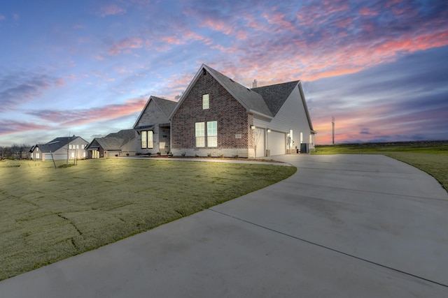 view of front of home featuring a lawn, central AC unit, and a garage