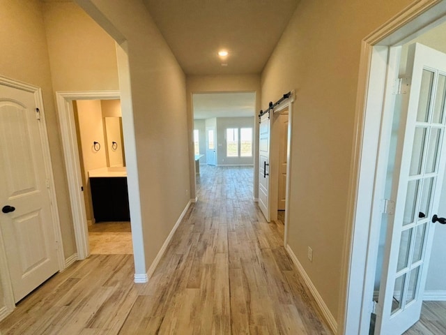 hall with a barn door and light hardwood / wood-style floors