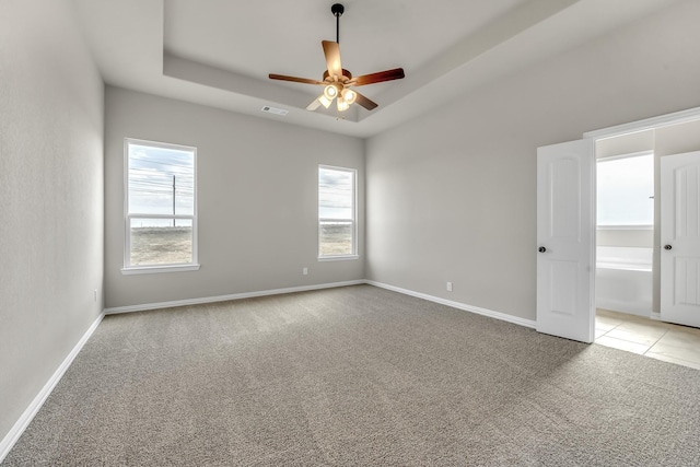 carpeted empty room with ceiling fan and a raised ceiling