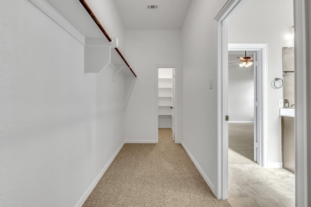 walk in closet with light carpet and ceiling fan