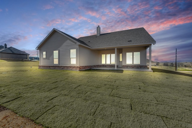 back house at dusk with a lawn