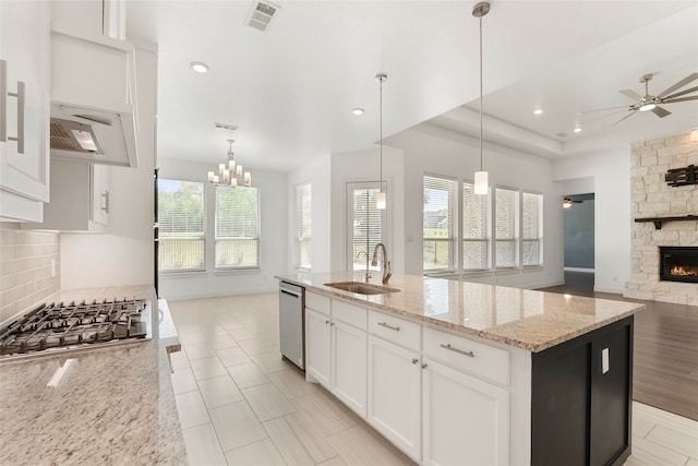 kitchen featuring appliances with stainless steel finishes, decorative light fixtures, a center island with sink, and a healthy amount of sunlight