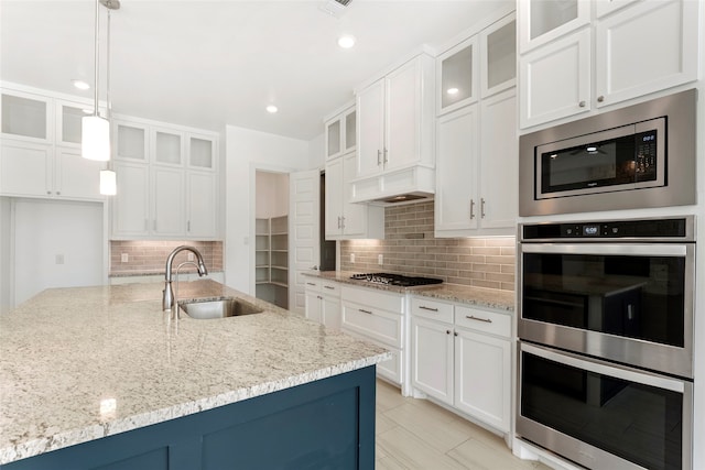 kitchen featuring white cabinets, sink, decorative light fixtures, appliances with stainless steel finishes, and light stone countertops