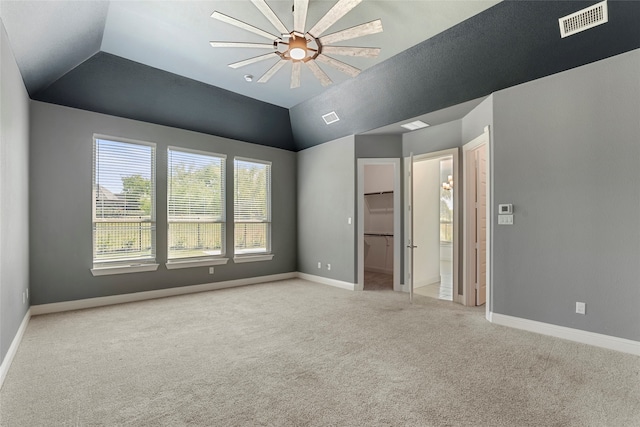 unfurnished bedroom featuring ceiling fan, light colored carpet, a spacious closet, lofted ceiling, and connected bathroom