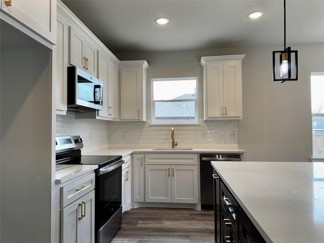 kitchen with sink, white cabinetry, pendant lighting, stainless steel appliances, and backsplash