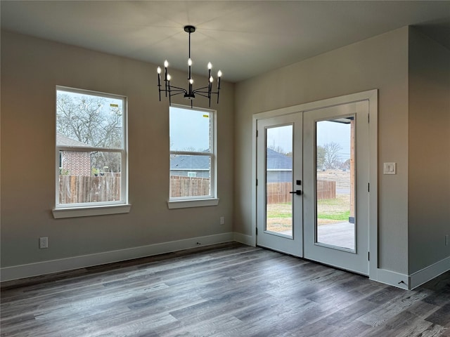 unfurnished dining area featuring an inviting chandelier, dark hardwood / wood-style flooring, and french doors