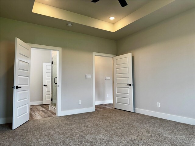 unfurnished bedroom featuring carpet floors, a raised ceiling, and ceiling fan