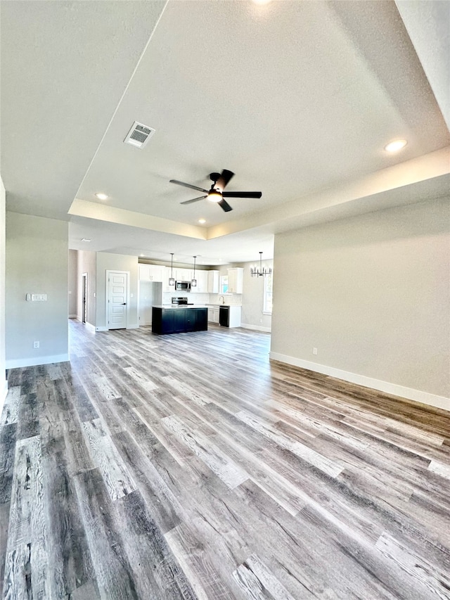 unfurnished living room featuring wood-type flooring, ceiling fan, and a textured ceiling