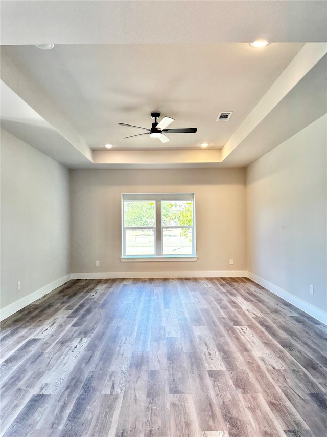 unfurnished room featuring a tray ceiling, ceiling fan, and hardwood / wood-style flooring