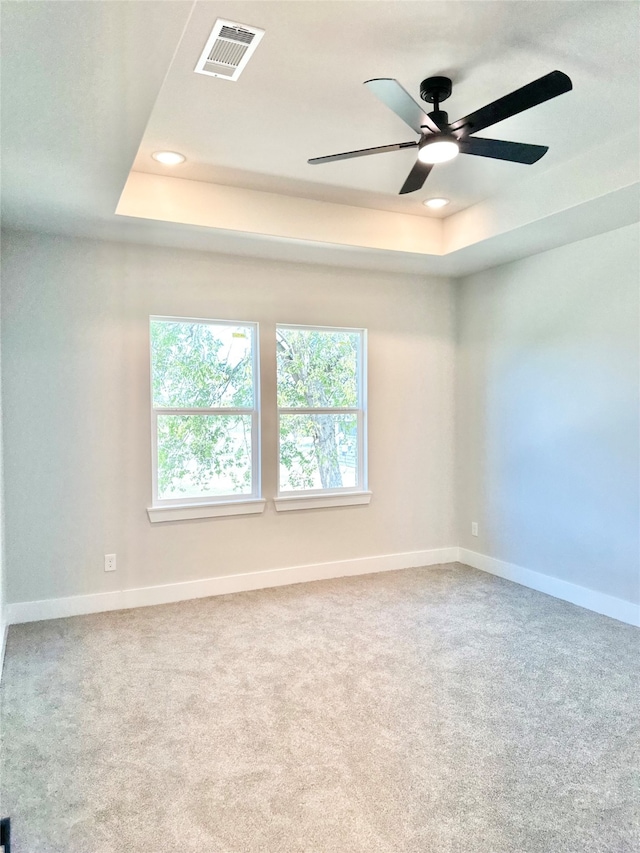 unfurnished room featuring carpet, ceiling fan, and a raised ceiling