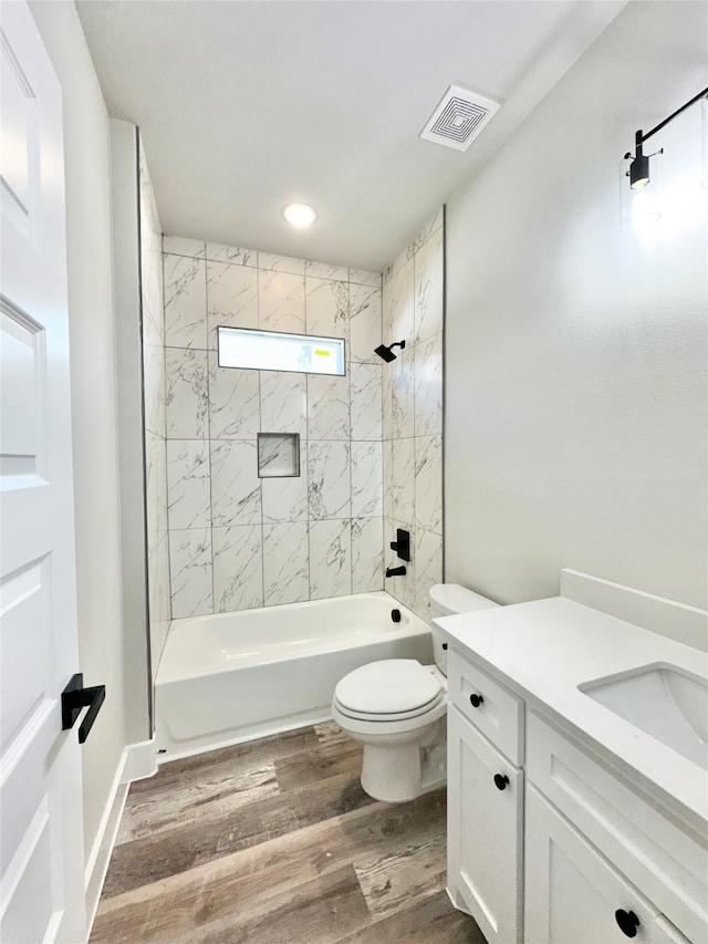 full bathroom featuring tiled shower / bath combo, toilet, vanity, and hardwood / wood-style floors