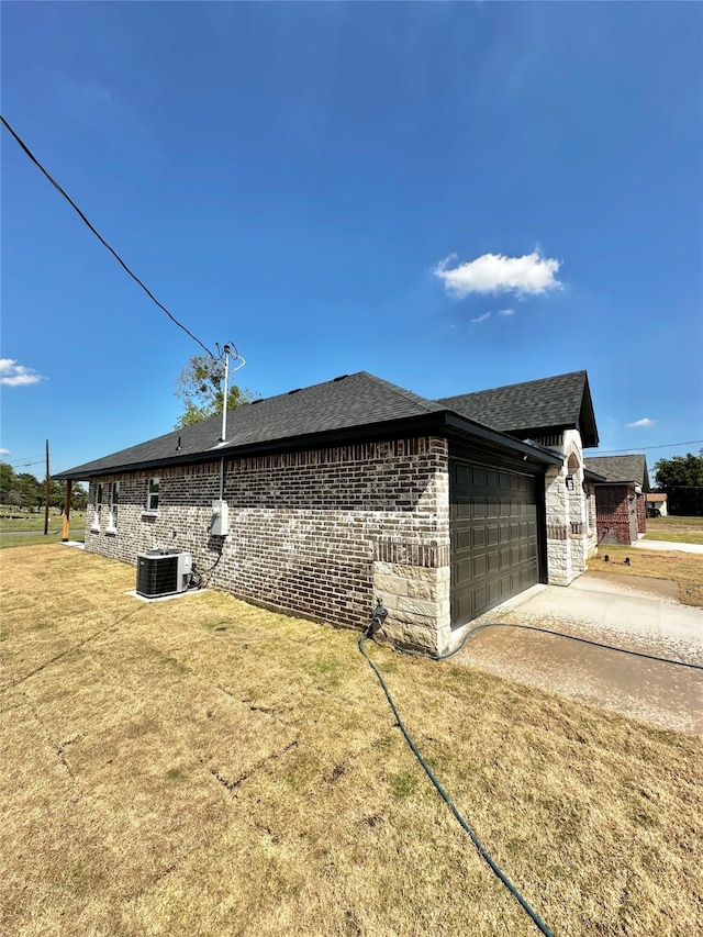 view of side of home with a lawn, cooling unit, and a garage