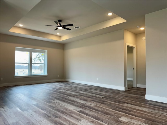 spare room featuring dark hardwood / wood-style flooring, a tray ceiling, and ceiling fan