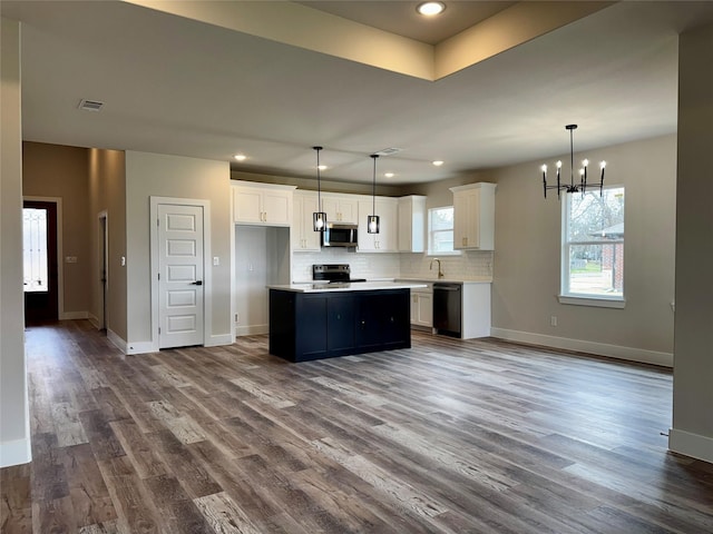 kitchen featuring stainless steel appliances, white cabinetry, a kitchen island, and hanging light fixtures