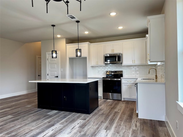 kitchen featuring sink, white cabinetry, stainless steel appliances, a center island, and decorative light fixtures