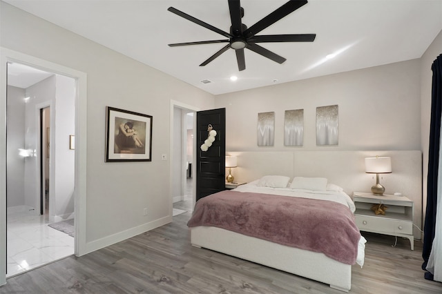 bedroom with ceiling fan, connected bathroom, and wood-type flooring