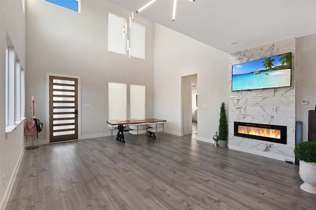 unfurnished living room with hardwood / wood-style flooring, a fireplace, and a towering ceiling