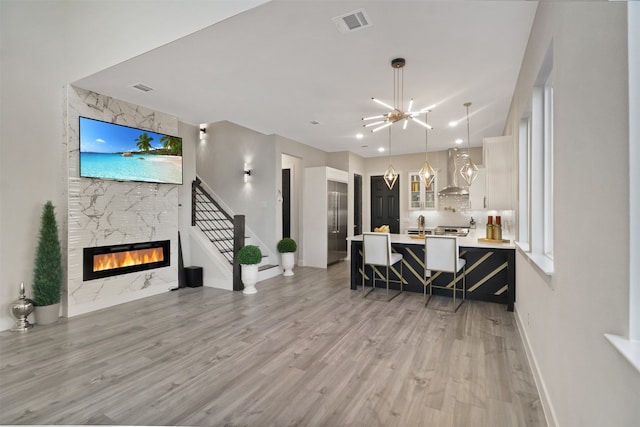 living room featuring a notable chandelier, light wood-type flooring, and a large fireplace