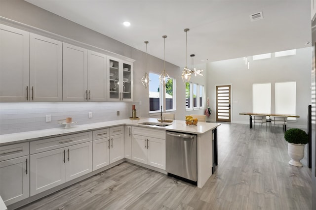 kitchen with hanging light fixtures, sink, white cabinetry, dishwasher, and decorative backsplash