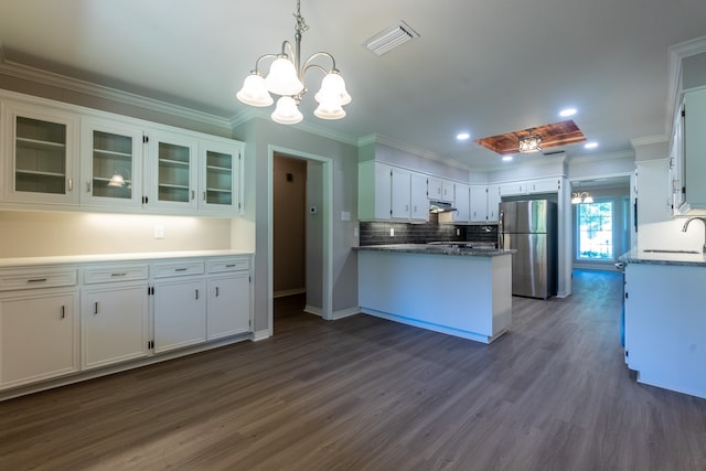 kitchen with white cabinetry, decorative light fixtures, ornamental molding, and stainless steel refrigerator