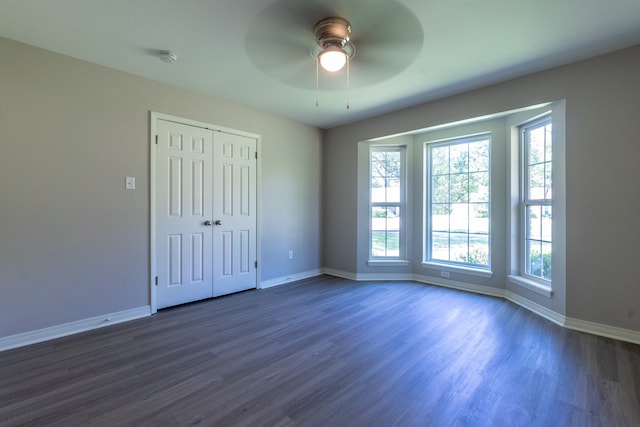 unfurnished bedroom featuring ceiling fan, dark hardwood / wood-style floors, and a closet