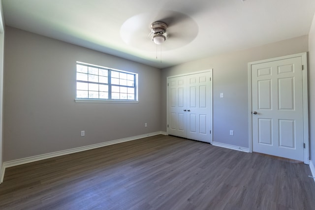 unfurnished bedroom featuring ceiling fan, dark hardwood / wood-style flooring, and a closet