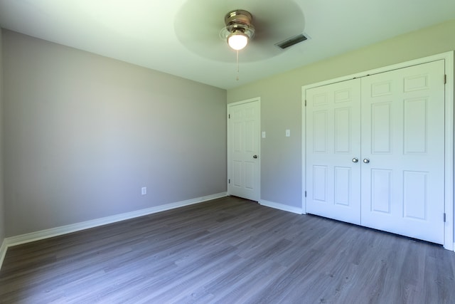 unfurnished bedroom with dark hardwood / wood-style floors, ceiling fan, and a closet