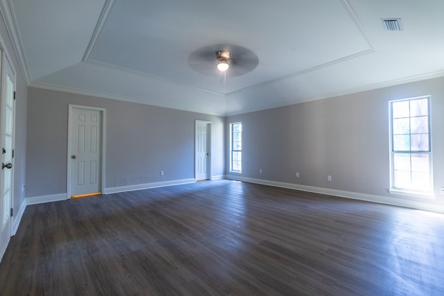 empty room with dark hardwood / wood-style flooring, a tray ceiling, crown molding, and ceiling fan