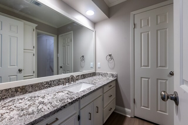 bathroom featuring ornamental molding, vanity, and wood-type flooring