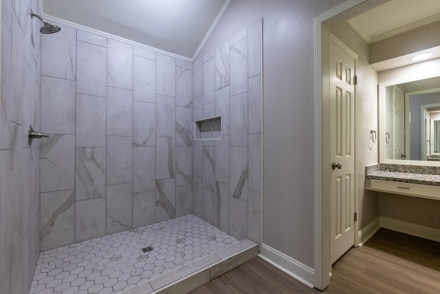 bathroom with crown molding, wood-type flooring, vanity, and a tile shower