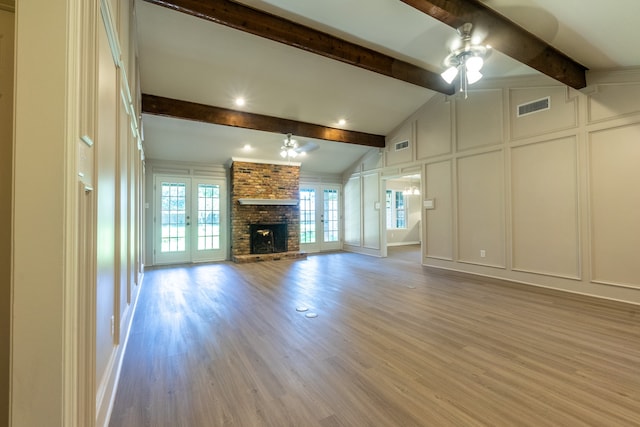 unfurnished living room with ceiling fan, lofted ceiling with beams, a brick fireplace, and light hardwood / wood-style flooring