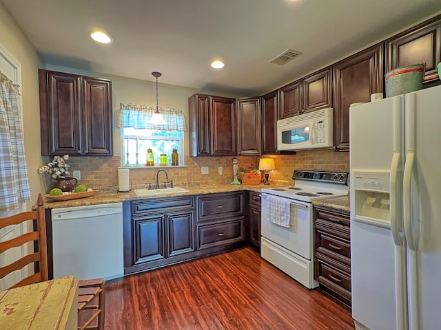 kitchen with light stone counters, hanging light fixtures, sink, white appliances, and dark wood-type flooring