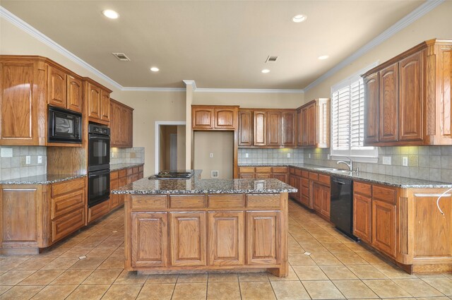 kitchen featuring light tile patterned flooring, black appliances, a center island, dark stone countertops, and crown molding