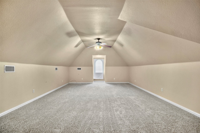 bonus room featuring a textured ceiling, vaulted ceiling, and carpet